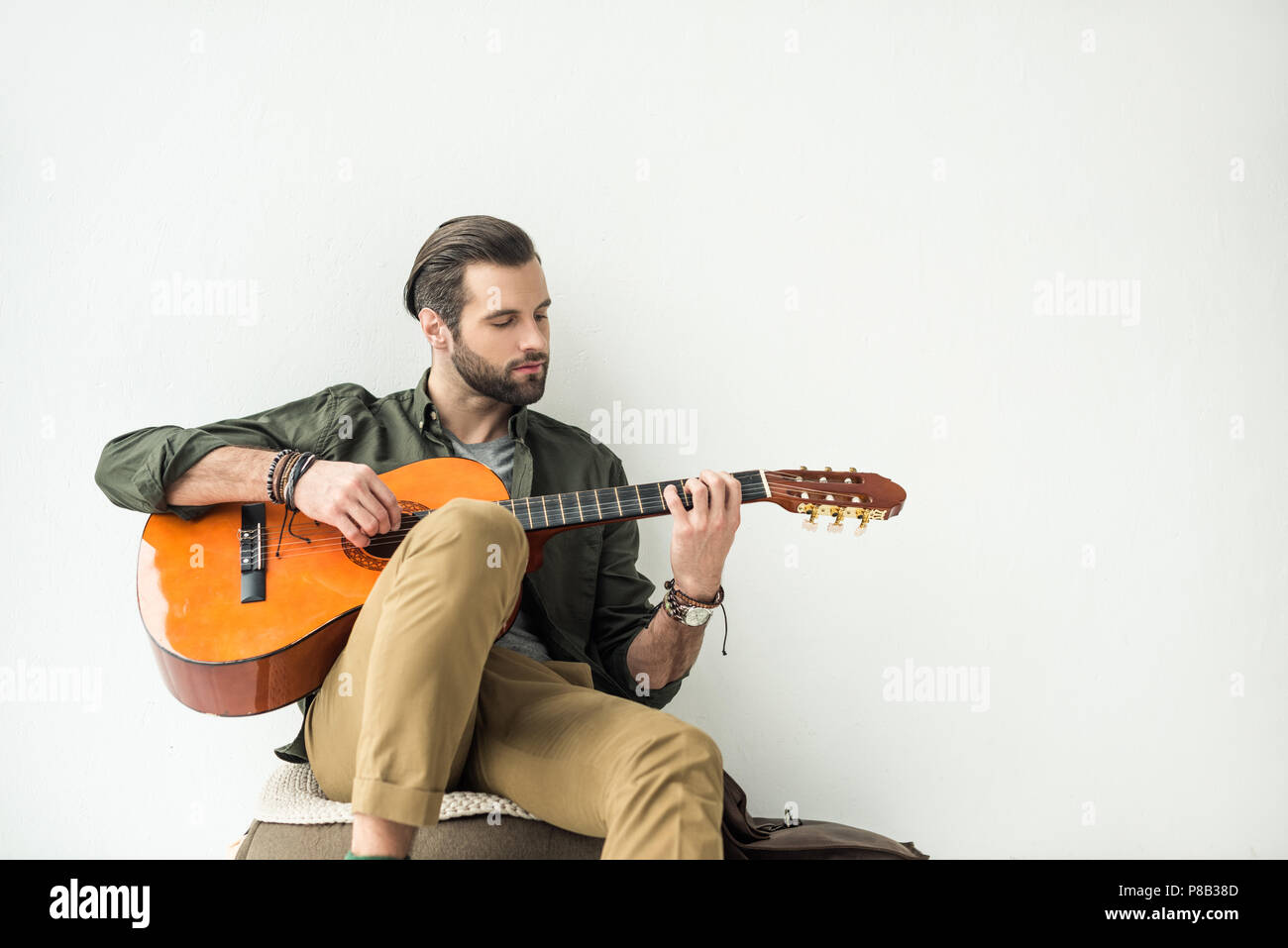 handsome man playing acoustic guitar and leaning on wall isolated on white p8b38d